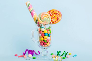 Masanın üzerinde açık arkaplanda renkli şekerler. Büyük kıvrımlı lolipoplar. Şekerci dükkanından leziz şekerlerle dolu yaratıcı bir kavanoz konsepti.