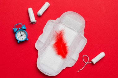 Alarm saatini hijyenik kadın tamponları ve regl pedleri ile çalıyor. Tıbbi konsept kadın kritik günler ve regl dönemi. Kadın günlük hijyen. Boşluğu kopyala.