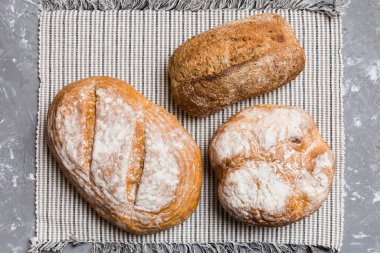 Kırsal masa manzaralı peçeteli taze pişmiş ekmek çeşitleri. Sağlıklı mayasız ekmek. Fransız ekmeği.