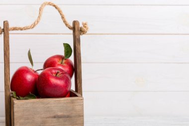Tahta kutuda olgun kırmızı elmalar. Beyaz ahşap arka planda.