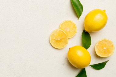 Renkli arka planda yeşil yapraklı taze limonlar, üst görünüm, metin için boşluk.