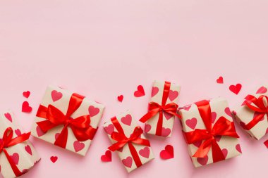 Top view photo of valentine day decorations gift box with red ribbon bow on colored background. Holiday gift boxes with top view.