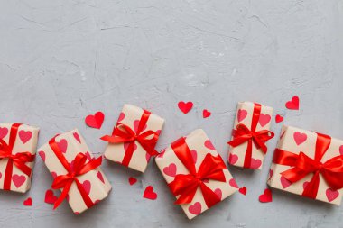 Top view photo of valentine day decorations gift box with red ribbon bow on colored background. Holiday gift boxes with top view.