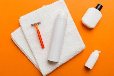 Tıraş Adam seti. Traş makinesi, havlu, losyon ve renkli arka planda tıraş köpüğü. Erkekler banyo aksesuarları üst görünüm.