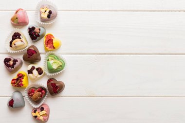 chocolate sweets in the form of a heart with fruits and nuts on a colored background. top view with space for text, holiday concept.