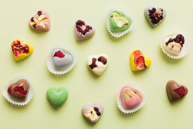 chocolate sweets in the form of a heart with fruits and nuts on a colored background. top view with space for text, holiday concept.