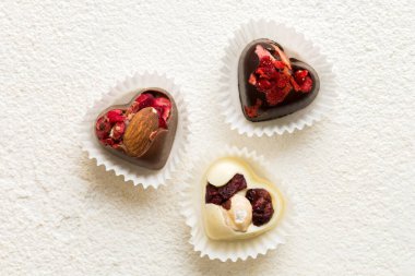 chocolate sweets in the form of a heart with fruits and nuts on a colored background. top view with space for text, holiday concept.