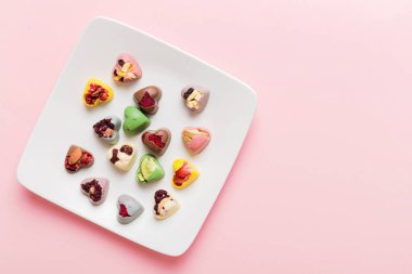 Plate with different chocolate on colored background. Assortment of fine chocolates top view vith copy space Health and obesity concept.