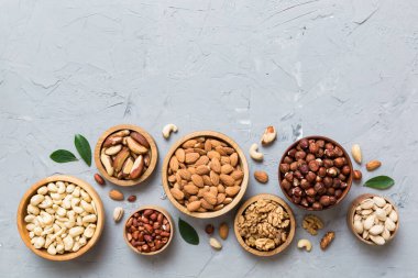 mixed nuts in wooden bowl. Mix of various nuts on colored background. pistachios, cashews, walnuts, hazelnuts, peanuts and brazil nuts.