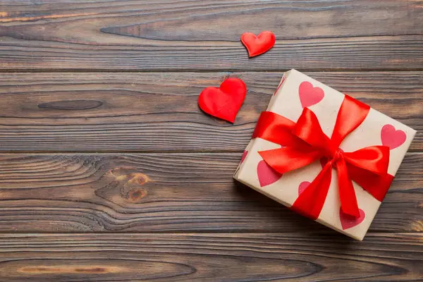 Top view photo of valentine day decorations gift box with red ribbon bow on colored background. Holiday gift boxes with top view.