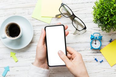Mesajınız veya bilgi içeriğiniz için boş bir kopya ekranı olan akıllı telefonları tutan kadın ellerinin üst görünümü. üst görünümde telefon beyaz ekranı kullanan kadın eli.