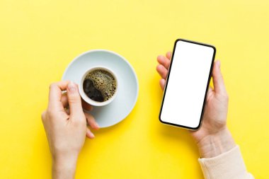 Mesajınız veya bilgi içeriğiniz için boş bir kopya ekranı olan akıllı telefonları tutan kadın ellerinin üst görünümü. üst görünümde telefon beyaz ekranı kullanan kadın eli.