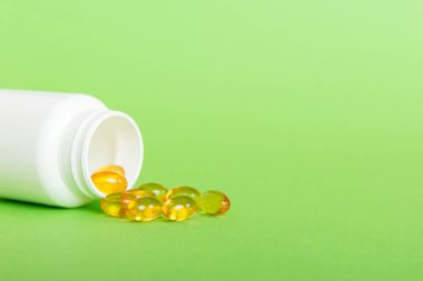 Yumuşak jel hapları ve Omega-3 yağı hap şişesinden sızıyor. Jel kapsülleri beyaz yüzey şişesi. Omega 3, multivitamin, kalsiyum, antibiyotik. Sağlığa. Dokunulmazlık.