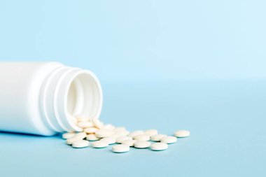 Medicine bottle and white pills spilled on a light background. Medicines and prescription pills flat lay background. White medical pills and tablets spilling out of a drug bottle.
