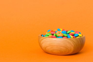 Renkli arka planda bir kasede çok renkli şekerler. Doğum günü ve tatil konsepti. Kopyalama alanı olan üst görünüm.