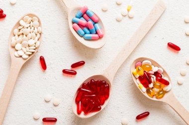 Renkli bir arka planda kaşıkta vitamin kapsülleri. Haplar sağlıklı bir yemek olarak sunuldu. Kırmızı yumuşak jel vitamin takviye kapsülleri kaşık üzerinde.