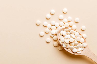 Renkli arka planda bir yığın beyaz hap. Tabletler masaya saçılmış. Kırmızı yumuşak jelatin kapsül yığını. Vitaminler ve beslenme takviyeleri konsepti.