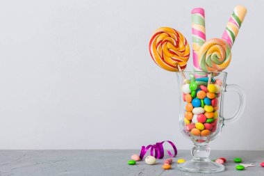 Masanın üzerinde açık arkaplanda renkli şekerler. Büyük kıvrımlı lolipoplar. Şekerci dükkanından leziz şekerlerle dolu yaratıcı bir kavanoz konsepti.