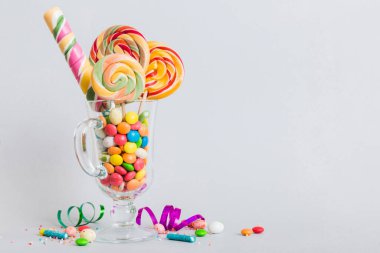 Masanın üzerinde açık arkaplanda renkli şekerler. Büyük kıvrımlı lolipoplar. Şekerci dükkanından leziz şekerlerle dolu yaratıcı bir kavanoz konsepti.