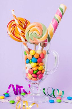 Masanın üzerinde açık arkaplanda renkli şekerler. Büyük kıvrımlı lolipoplar. Şekerci dükkanından leziz şekerlerle dolu yaratıcı bir kavanoz konsepti.