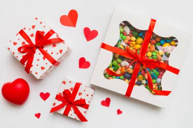Valentine day composition: sweet candy, with gift boxes with bow and red felt hearts, photo template, background. Top View with copy space.