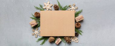 Noel kompozisyonu düzdü. Kare kağıt boş, çam ağacı dalları, renkli arka planda noel süslemeleri. Üst görünüm, metin için boşluk kopyala.