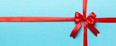 Kırmızı kurdelenin üst görüntüsü yuvarlandı ve kırmızı fiyonk renkli arka planda izole edildi. Kopyalama alanı olan düz.