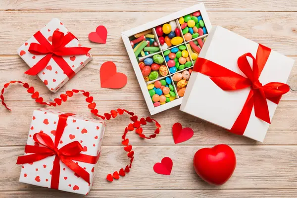 Valentine day composition: sweet candy, with gift boxes with bow and red felt hearts, photo template, background. Top View with copy space.