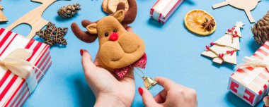 Mavi arka planda kadın ellerinde ren geyiği manzarası. Noel süsleri. Yeni yıl tatili konsepti.