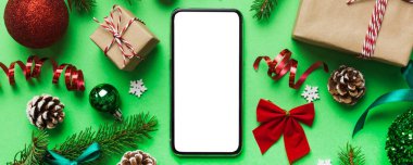 Digital phone mock up with rustic Christmas decorations for app presentation top view with empty space for you design. Christmas online shopping concept. Tablet with copy space on colored background.