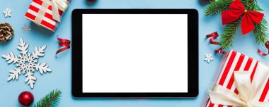 Digital tablet mock up with rustic Christmas decorations for app presentation top view with empty space for you design. Christmas online shopping concept. Tablet with copy space on colored background.