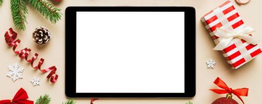 Digital tablet mock up with rustic Christmas decorations for app presentation top view with empty space for you design. Christmas online shopping concept. Tablet with copy space on colored background.