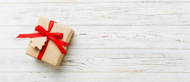 wrapped christmas or other holiday handmade present in paper with colored ribbon. Present box, decoration of gift on colourfull table, top view with copy space.