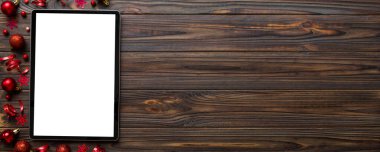 Noel alışverişi boş beyaz ekranlı tablet bilgisayardan yapılıyor. Renkli arka planda noel süsleme toplarıyla fotokopi alanı olan tablet. Kış tatillerinde satış geçmişi.