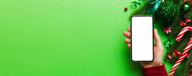 Mesaj atmak için yeri olan bir Noel modeli. Noel reklamı, uygulama şablonu. Masa arkasında boş ekran olan el ele tutuşan telefon. Mutlu yıllar ve Xmas Flat.