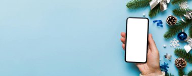 Mesaj atmak için yeri olan bir Noel modeli. Noel reklamı, uygulama şablonu. Masa arkasında boş ekran olan el ele tutuşan telefon. Mutlu yıllar ve Xmas Flat.