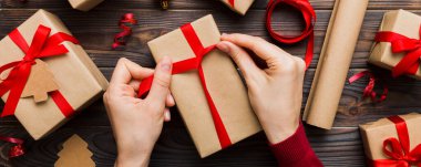 Kadınlar Noel tatili için sürpriz hediyeler hazırlıyor. İş yerinde el aletleri ve manzarayla oturuyor. Renkli masada Noel hediyesini paketleyen kadın..