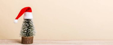 One small Christmas tree with santa hat on colored background. new year decoration with copy space.
