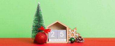 25 december. Christmas composition on colored background with a wooden calendar, with a gift box, toys, bauble copy space.