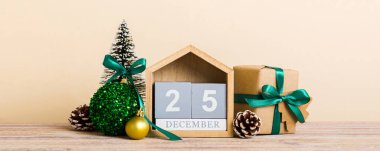 25 december. Christmas composition on colored background with a wooden calendar, with a gift box, toys, bauble copy space.