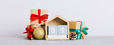 1 january. Christmas composition on colored background with a wooden calendar, with a gift box, toys, bauble copy space.