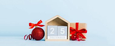 25 december. Christmas composition on colored background with a wooden calendar, with a gift box, toys, bauble copy space.