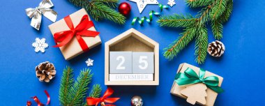 Christmas calendar 25 december. Christmas gift, fir branches, pine cones. Flat lay, top view. New Year decorations on a colored background.