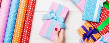 Elinde hediye kutusuyla neşeli tahta arka planda gezen bir kadının en iyi görüntüsü. Sarılmış ambalaj kağıdı ve Noel süsleri. Yeni yıl zaman kavramı.