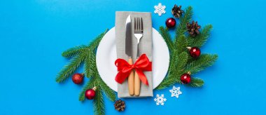 Noel süsleri, tabaklar, inekler, çatallar ve kaşıklarla Noel sofrası. Noel tatili geçmişi. Üst görünüm.