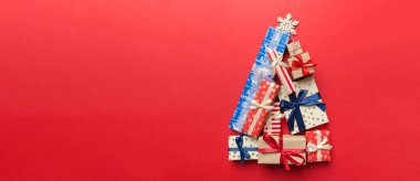 Renkli arka planda güzel paketlenmiş hediyelerden yapılmış Noel ağacı, yukarıdan görünüyor. Kopya alanı olan en küçük hediye kutusu konsepti.