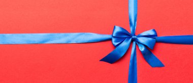 Mor kurdelenin üst görüntüsü yuvarlandı ve pembe fiyonk renkli arka planda izole edildi. Kopyalama alanı olan düz.