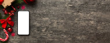 Digital phone mock up with rustic Christmas decorations for app presentation top view with empty space for you design. Christmas online shopping concept. Tablet with copy space on colored background.