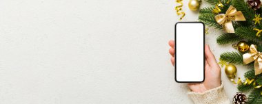 Mesaj atmak için yeri olan bir Noel modeli. Noel reklamı, uygulama şablonu. Masa arkasında boş ekran olan el ele tutuşan telefon. Mutlu yıllar ve Xmas Flat.