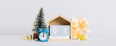 Christmas composition on colored background with a wooden calendar, with a gift box, toys, bauble copy space.